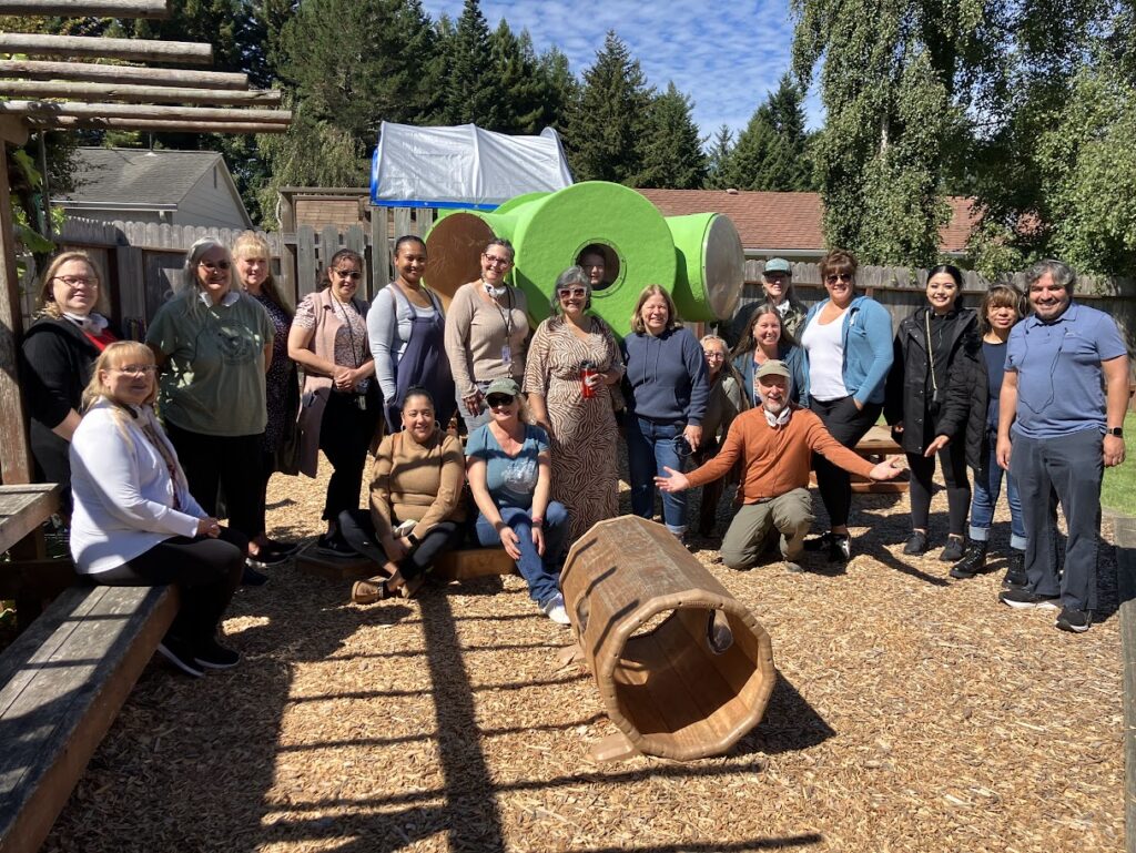 Group of childcare and speaker in natural playspace